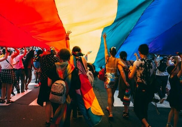 gay and lesbian people walking under a giant LGBT flag