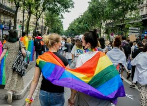 Two women with an LGBTQ flag around them 
