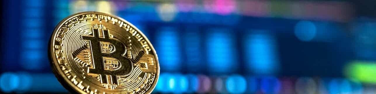 A physical golden Bitcoin with a blue background