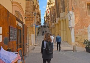 Old street in Malta with tourists exploring the buildings - European country progressive and welcoming for gay and lesbian people