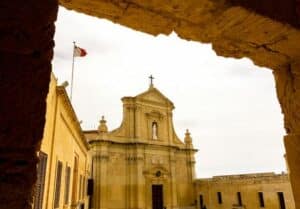 A historic building with a Malta flag waving on the top 