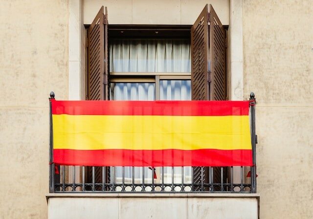 A balcony in Spain with a Spanish flag hanging on the railing.