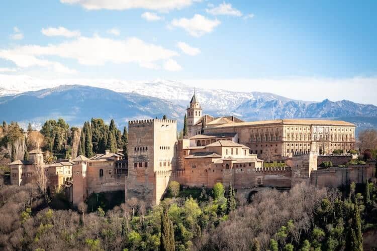 Alhambra palace in Granada, Spain, with snowy mountains in the background.