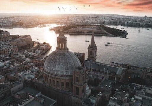 Ariel view of the capital of Malta in the middle and a body of water in the middle of the city. 