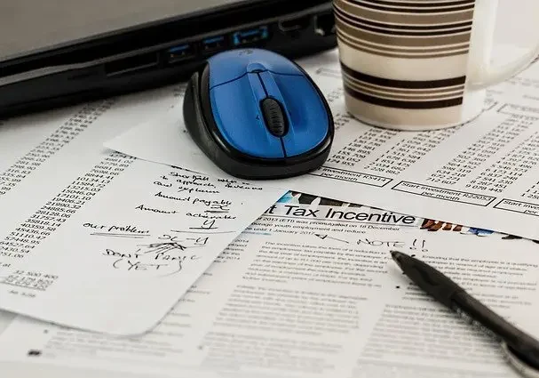 a laptop, pen, coffee and documents on a desk