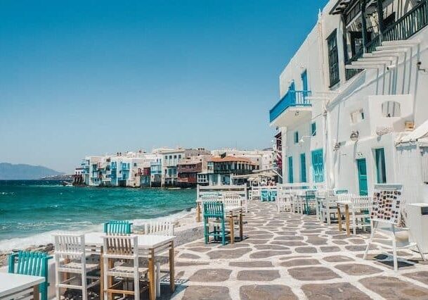 A sea-view restaurant in Greece with tables and chairs outside. 