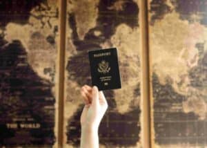Hand holding up a passport against a map mural - Obtain a second passport through Citizenship by Investment