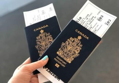 person holding a Canadian passport with travel tickets after getting Canadian citizenship