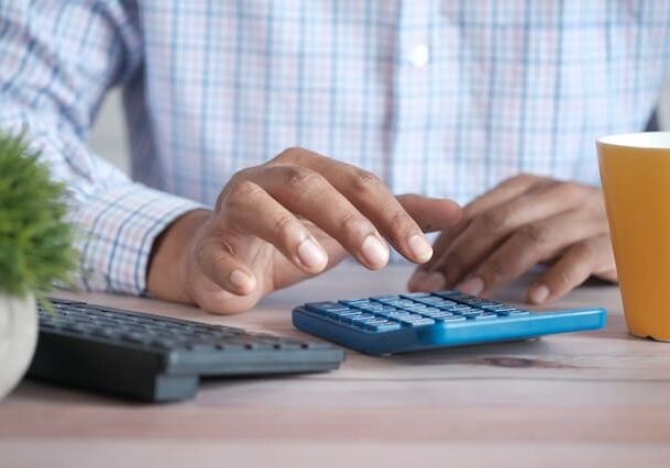 Man using a calculator at a desk with a cup of coffee and a keyboard in front of him - why country of tax residence matters