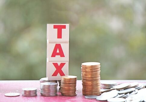 The word tax on a stack of coins