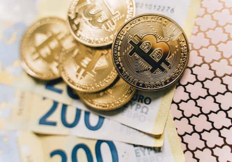 Bitcoin coins and Euro notes laid out on a golden pattern - crypto tax explained