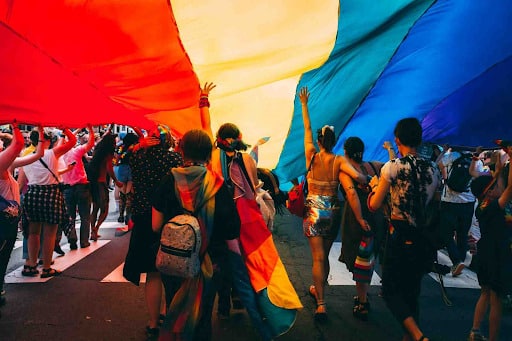 People holding up a large pride flag 
