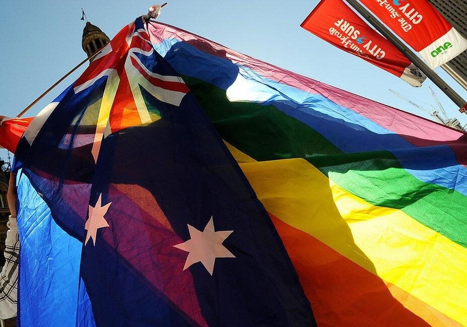 Person's silhouette shining through a Pride flag at a protest - Australia as an LGBTQ-friendly country