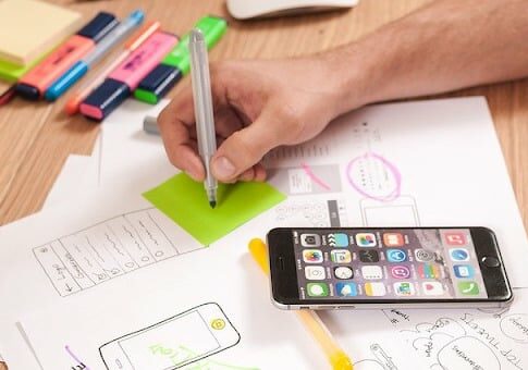 A person studying with multi colored highlighters and phone next to it. 