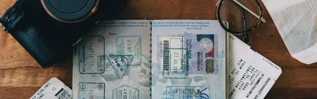 Opened passport with boarding passes, a camara and glasses. Residency vs Citizenship
