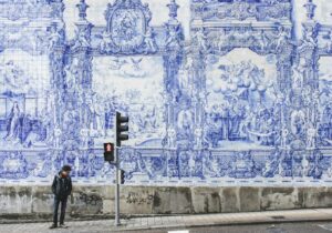 Man standing on a street in Portugal next to street light and a blue and white mural - Portugal Golden Visa