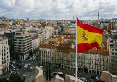 An overview of a city in Spain with the Spanish flag in the forefront. 