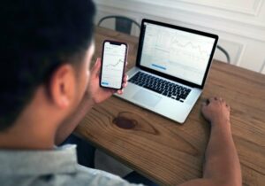 Man looking at his investments on a laptop and mobile phone