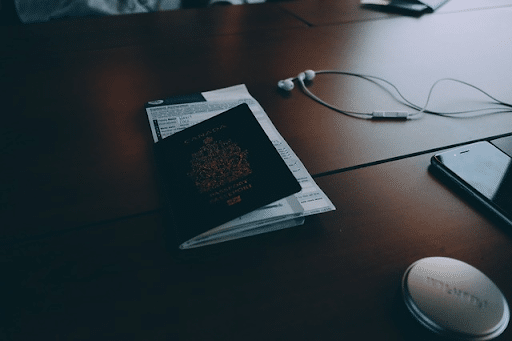 Passport with an airline ticket next to earphones and a smartphone - overview of how many citizenships you can have