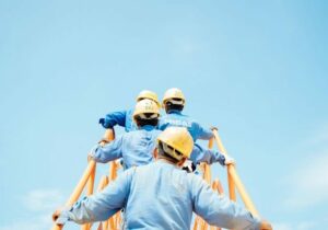 people climbing a ladder with hard hats on