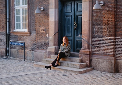 Red-haired woman sitting on chairs in front of a brick building - one of the safest countries for women in Europe