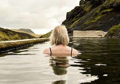 Blonde woman relaxing in a natural pool in Iceland - safe Nordic country for women