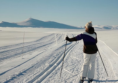 View of woman skiing in Norway with snow as far as the eye can see - Norway as a safe country for women