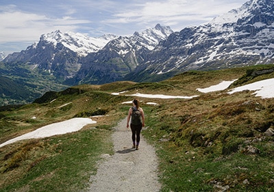 Woman hiking in Switzerland with snow-capped mountains in front of her - one of the safest European countries for women