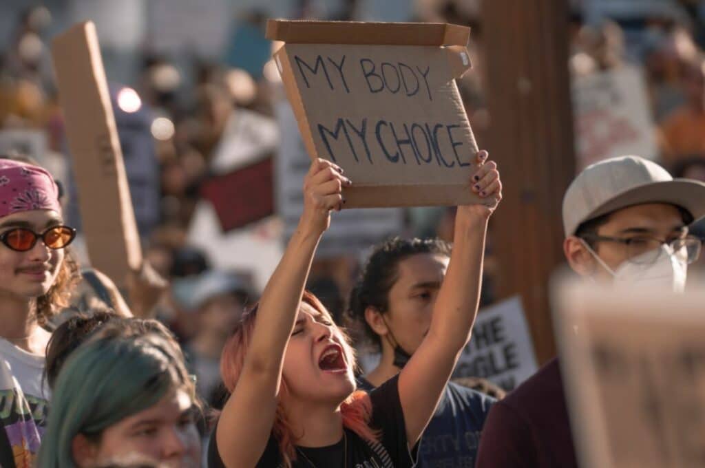 Woman holding a sign saying "My Body, My Choice" in a street demonstration