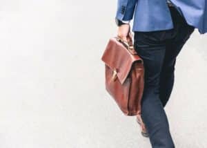 A person walking while holding a leather briefcase