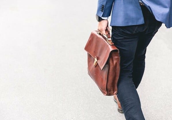 A man walking while holding a leather brief case 