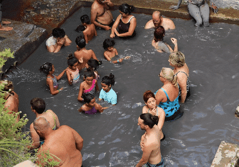 group of adults and children taking a mud bath at st lucia Drive-in Volcano