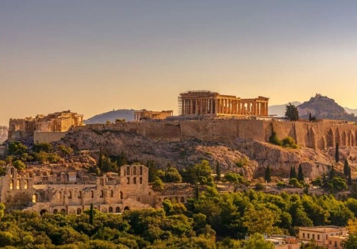A view of brown monument building in Greece with trees around them. 