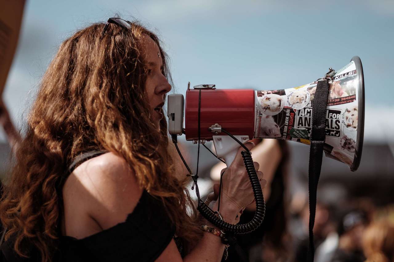 redhead woman chanting through a megaphone at a demonstration