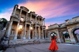 Woman in a red dress exploring ancient ruins in Turkey at sunset, symbolizing culture, heritage, and the lifestyle benefits of Turkey citizenship.