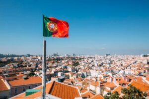 Portugal flag waving over an old town in Portugal - Golden Visa program in EU