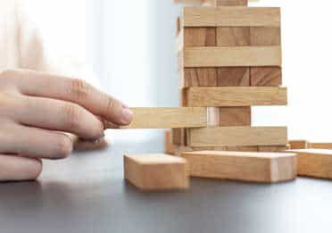 Man playing with Jenga blocks on a desk - investing internationally