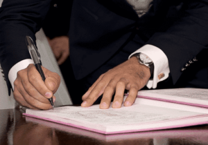 Man in black suit signing a contract - Benefits of tax treaties