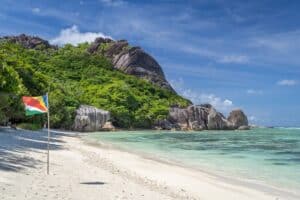 Flag of Seychelles on a beach on a bright sunny day with a hilltop in the background - best places to retire in the world