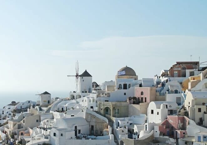 A coastal village in Greece with white houses stacked on a hillside overlooking the sea.