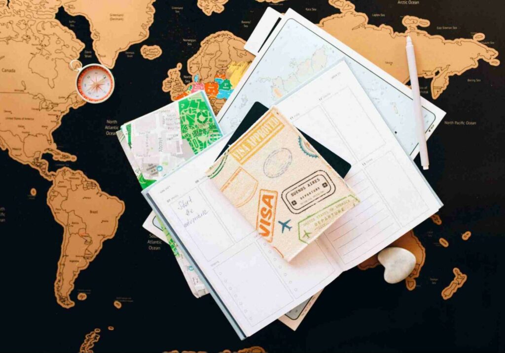 Passport, maps, a pen and compass laid out on a huge map of the world - golden passport countries
