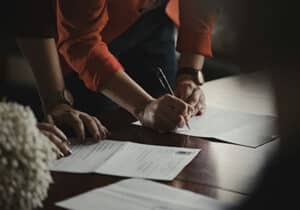 person signing documents on a table for st kitts and nevis citizenship by investment