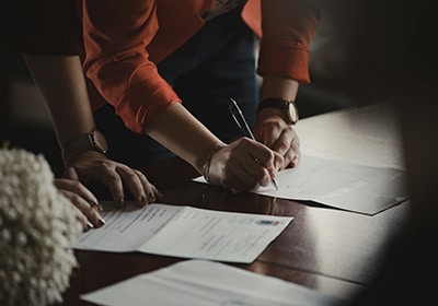 person signing documents on a table for st kitts and nevis citizenship by investment