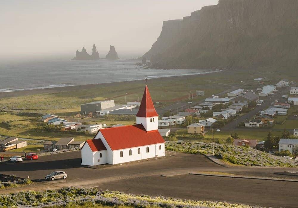 Red-roofed building in the city of Reykjavik in Iceland with looming mountains in the distance - best European countries for quality of life