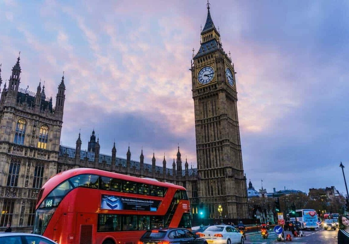 Low angle view of Big Ben with an iconic red bus driving by - countries to live in as an expat in Europe