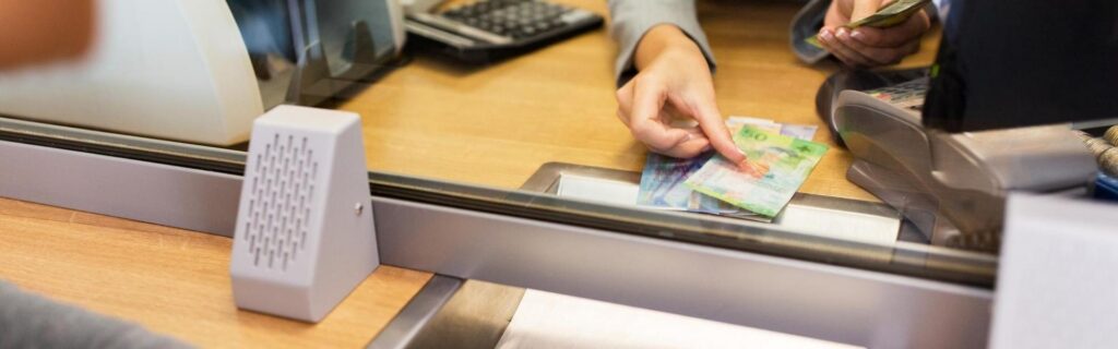 st lucia bank teller handing easter caribbean dollards to customer