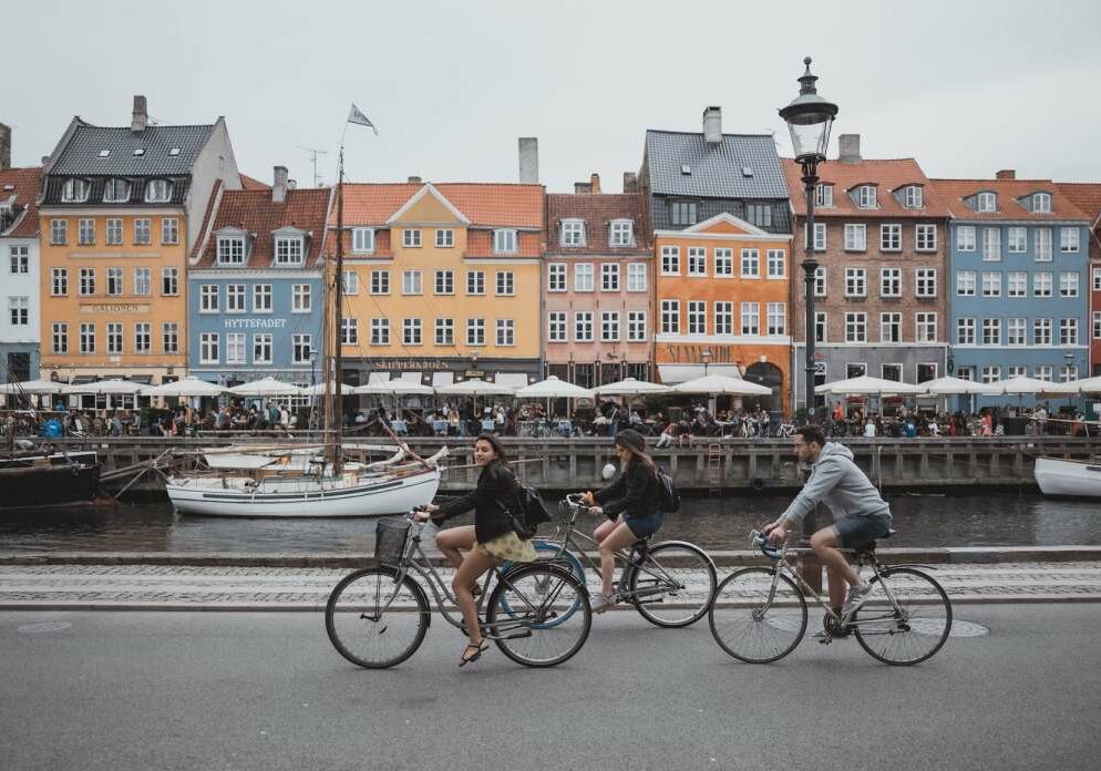 Colorful houses in Denmark with people cycling by on bikes - Best Countries to Live in the World for Expats 