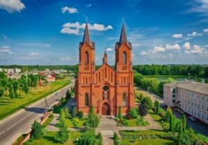 Church of Saints Simon and Helena in Belarus with bright green garden in the foreground - crypto currency haven for tax benefits