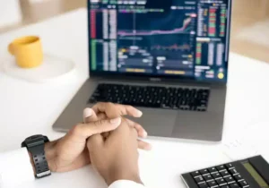 Hands clasped in front of a laptop showing crypto currency stocks - how crypto tax works