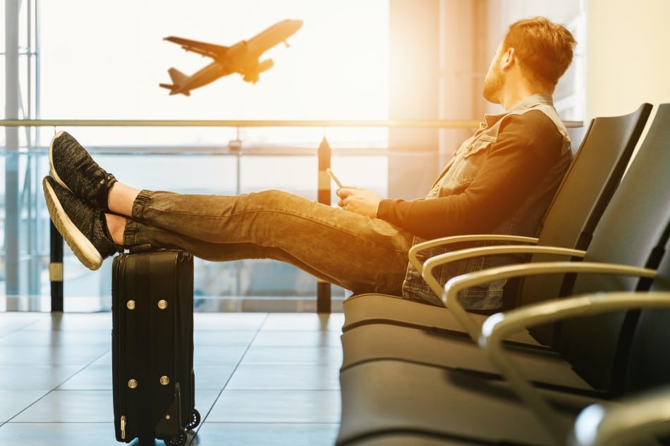 US passport holder looking outside airport window at airplane taking off